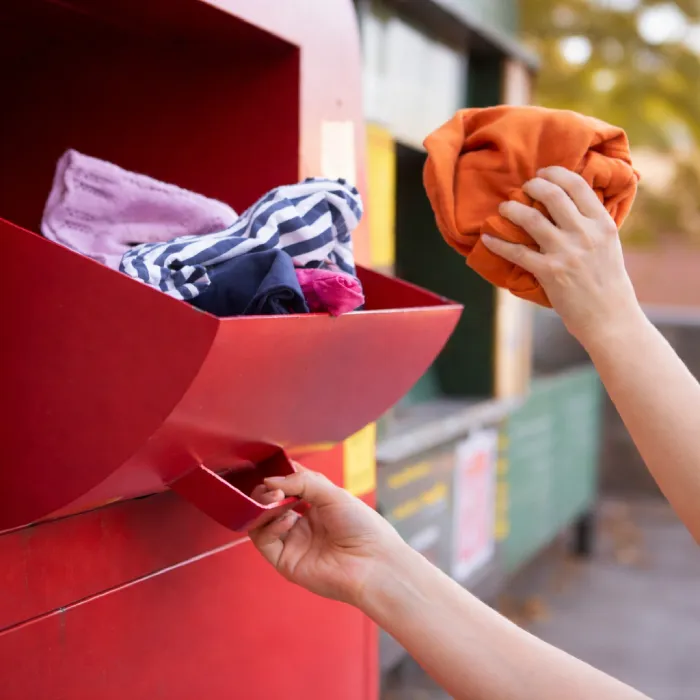 Persona depositando prendas en un punto de recogida de ropa usada