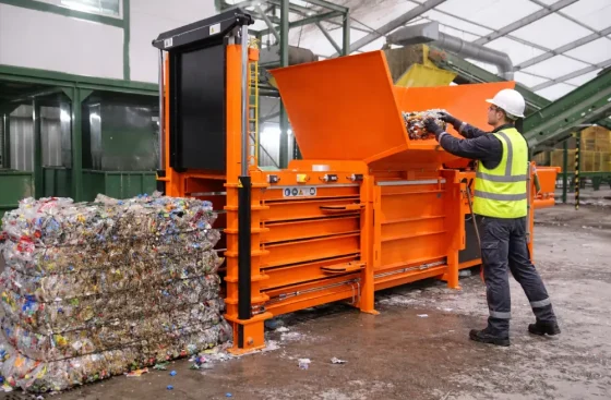 Operario gestionando residuos plásticos con compactadora en almacén